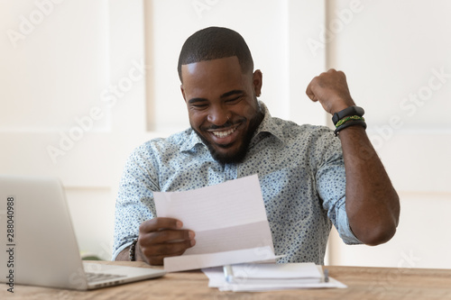 Happy african american guy received banking loan approval. photo
