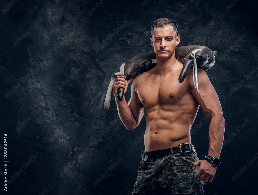 Muscular attractive hot man is holding weight bag while posing for photographer.
