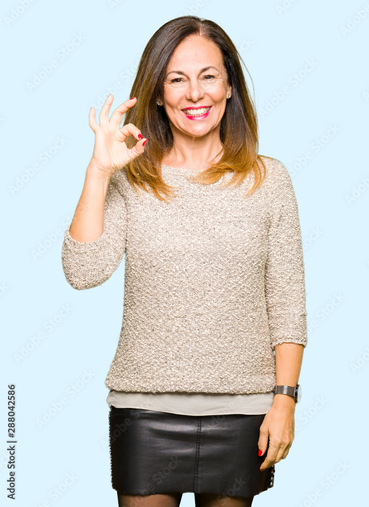 Beautiful middle age woman wearing fashion sweater smiling positive doing ok sign with hand and fingers. Successful expression. Beautiful middle age woman wearing fashion sweater smiling positive doing ok sign with hand and fingers. Successful expression.