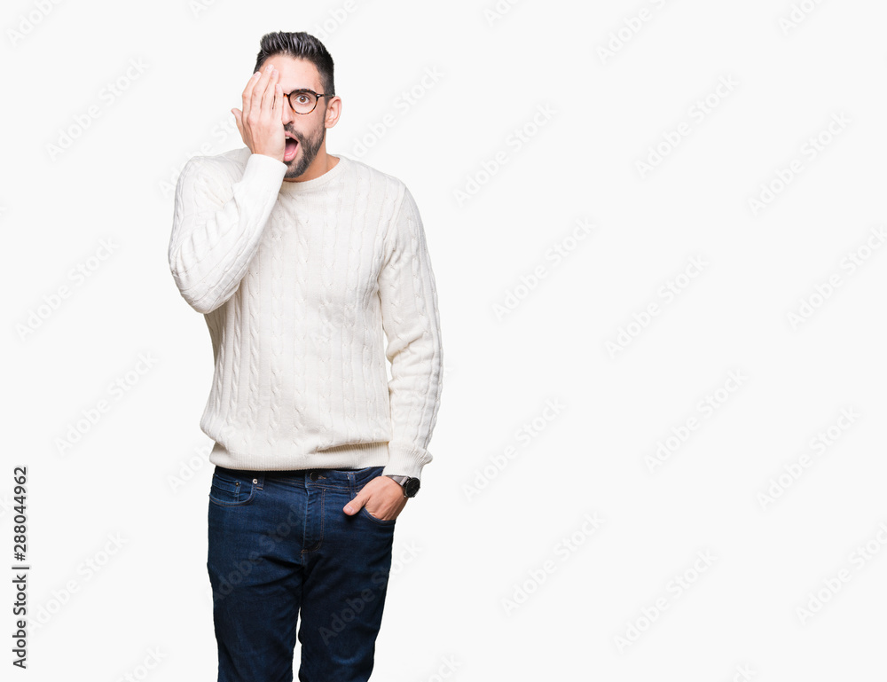 Young handsome man wearing glasses over isolated background covering one eye with hand with confident smile on face and surprise emotion. Young handsome man wearing glasses over isolated background covering one eye with hand with confident smile on face and surprise emotion.