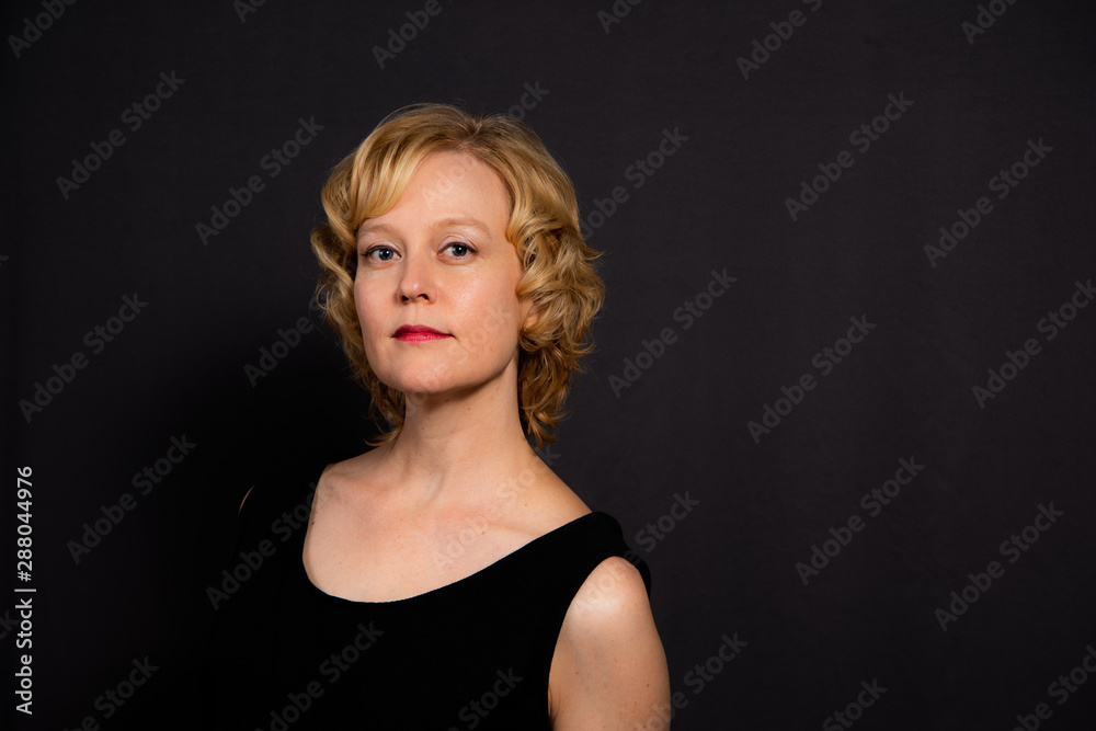 Studio portrait of a woman with a thoughtful, serious expression against a dark background. Studio portrait of a woman with a thoughtful, serious expression against a dark background.