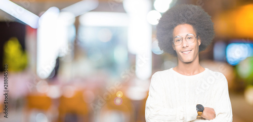 Young african american man with afro hair wearing glasses happy face smiling with crossed arms looking at the camera. Positive person.