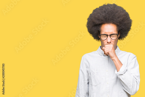 Young african american man with afro hair wearing glasses feeling unwell and coughing as symptom for cold or bronchitis. Healthcare concept.