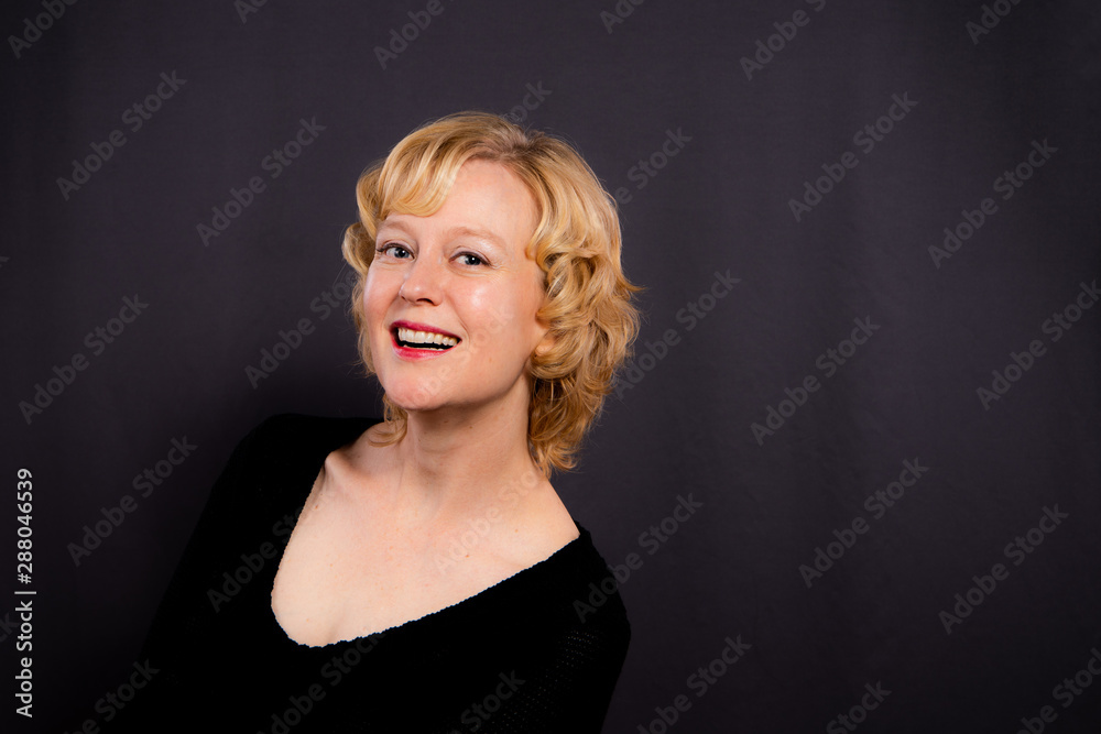 Studio portrait of a beautiful woman in her forties with short, curly blond hair. Studio portrait of a beautiful woman in her forties with short, curly blond hair.