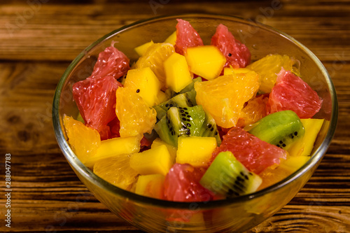 Salad with mango  oranges  grapefruit and kiwi fruits in a glass bowl on wooden table