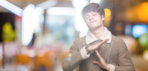 Young handsome man wearing winter coat over isolated background Doing time out gesture with hands, frustrated and serious face