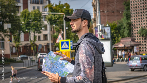 Young happy tourist sightseeing in city. Cheerful man wanderer with trendy look searching direction on location map while traveling abroad in summer, happy tourist.  portrait of a man in hat. 