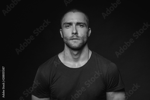 Black and White Muscle strong beautiful stripped male model with black t-shirt in denim blue jeans on black isolated font background