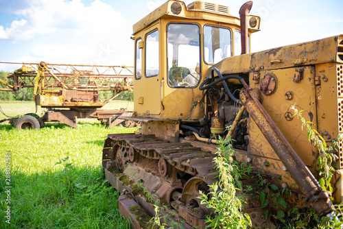 Abandoned farm equipment. The bulldozer covered with moss. Overgrown weeds tractor. Bulldozer is worth many  many years.