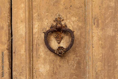 Italy, Apulia, Province of Lecce, Galatina. Rusty knocker on an old weathered wooden door. photo
