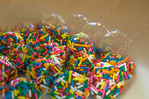 typical brazilian sweet at birthday parties, Brigadeiro, with colorful chocolate sprinkles on white plate