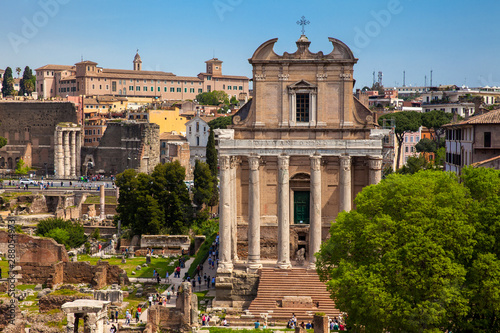 Tourists visiting the Roman Forum and the Temple of Antoninus and Faustina in Rome