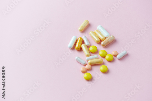 Vitamins and supplements on pink paper background. Concept for a healthy dietary supplementation. Copy space. 
