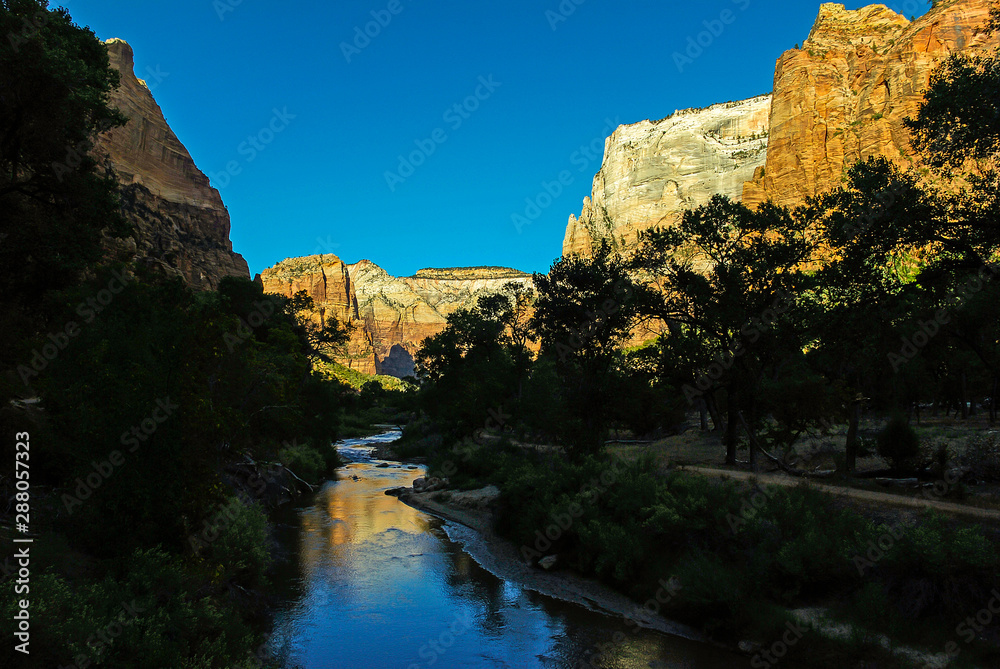 Emerald Pool Trail in Shadows of Mountains reflected in Virgin River in Zion National Park Utah