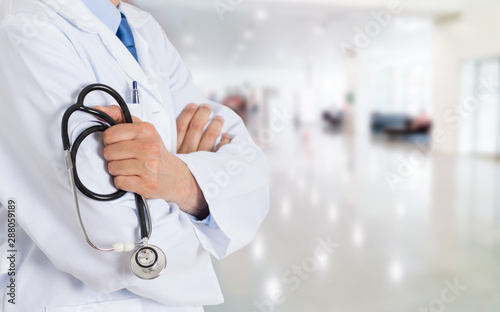 Cropped shot of an unrecognizable male doctor standing with his arms folded inside of a hospital during the day and copy space