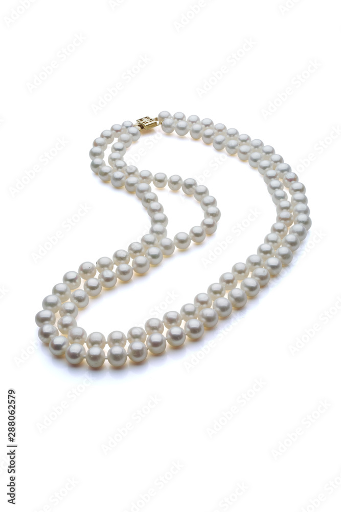 Double strand white pearl necklace with gold clasp. Set on a white background with a shadow under the pearls. Double strand white pearl necklace with gold clasp. Set on a white background with a shadow under the pearls.