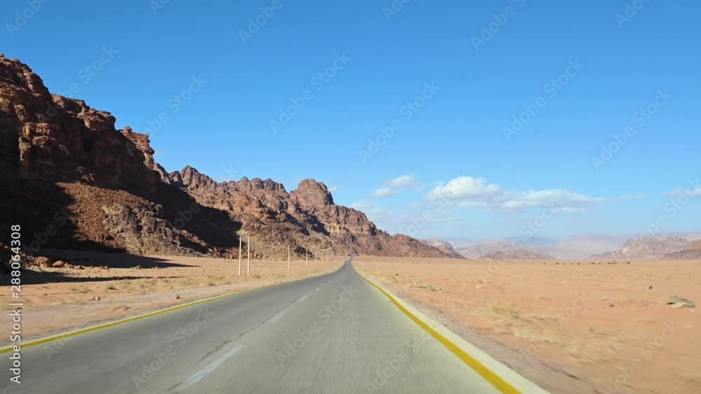 Driving on the Kings Highway (scenic route between Amman and Petra) Stunning road running through the Wadi Rum desert. Beautiful rocky mountains in the distance. Jordan. Driving on the Kings Highway (scenic route between Amman and Petra) Stunning road running through the Wadi Rum desert. Beautiful rocky mountains in the distance. Jordan.
