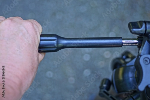 hand holds black plastic tripod handle on gray background