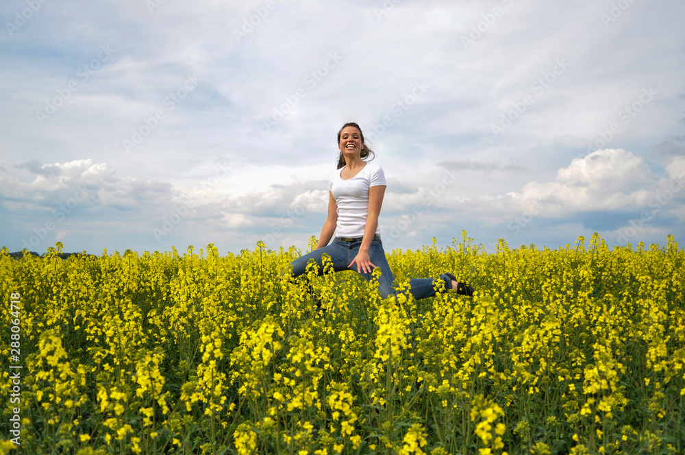 Girl Is Jumping In A Blooming Rapeseed Field Girl Is Jumping In A Blooming Rapeseed Field
