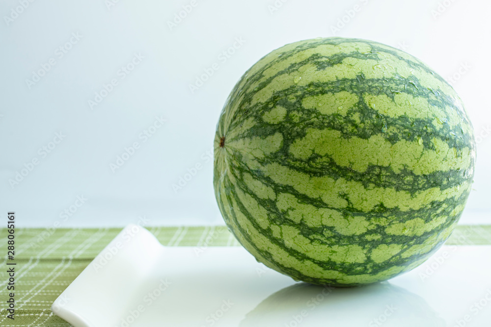 Whold watermelon on a white ceramic tray and table top Whold watermelon on a white ceramic tray and table top