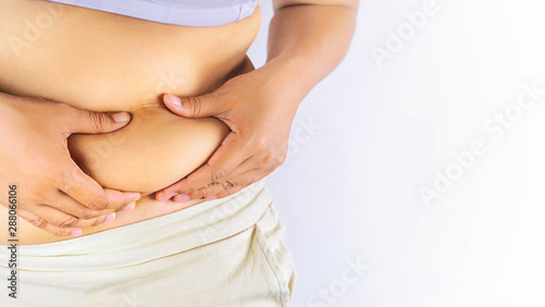 Fat woman is catching her belly area that has excess fat.