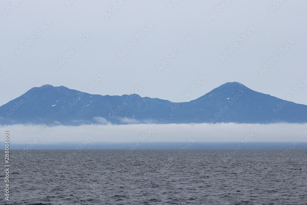 Iturup Island volcanoes on foggy horizon. The Sea of Okhotsk, Kuril Islands, Russia, claimed by Japan.
