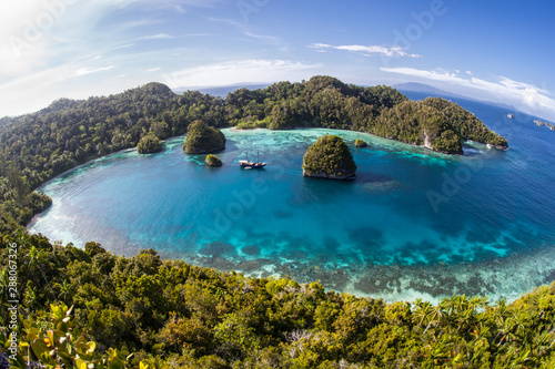 A small ship rests at anchor amid the tranquil seascape in Raja Ampat, Indonesia. This equatorial region is possibly the center for marine biodiversity.