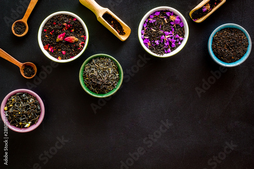 Assortment of dry tea in bowls frame on black background top view copyspace