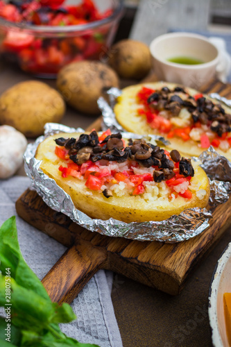 Baked stuffed potatoes with vegetables in foil. Homemade vegan food. 