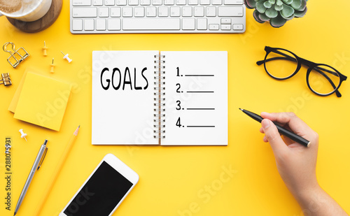 Goal concepts young female writing checklist with notepad on color desk table.business plan
