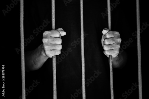 hand man hold steel in jail on black background.concept for prisoner,sadness,detain,erroneousness