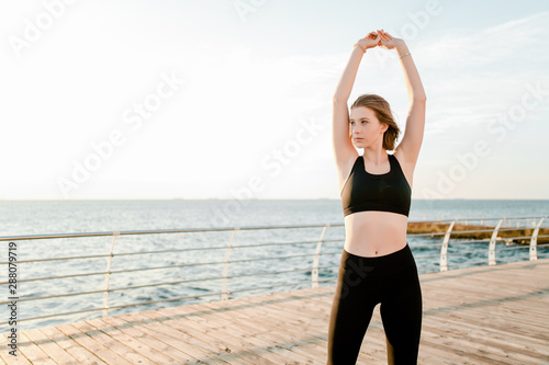 fit teenage girl stretching and doing fitness training on the beach