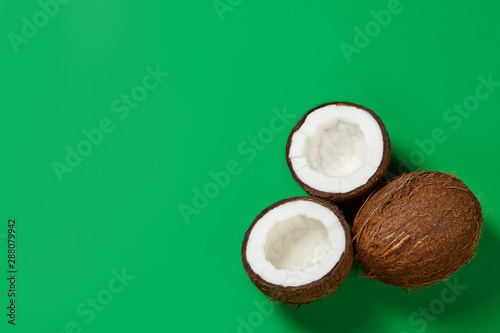 Coconut and half of coconut on green background with space for your text.