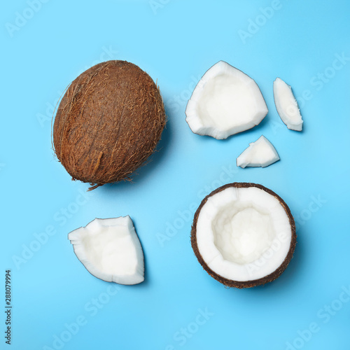 Whole and cracked coconuts on blue background. Creative concept.