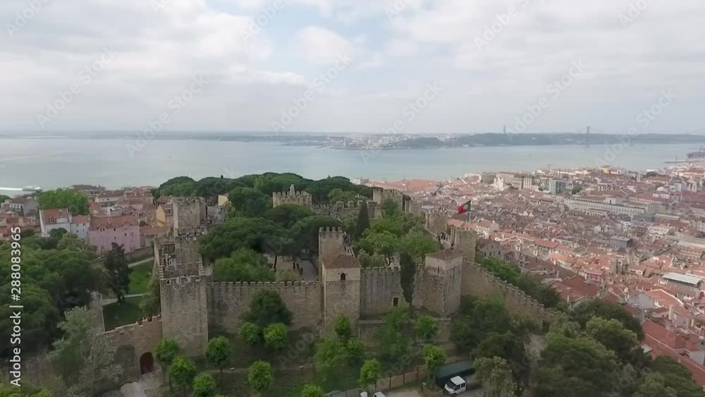 Rotating aerial view showing Sao Jorge Castle in Lisbon, with amazing views of the city, the river, and the famous 25th April Bridge and Christ the King in the background. Rotating aerial view showing Sao Jorge Castle in Lisbon, with amazing views of the city, the river, and the famous 25th April Bridge and Christ the King in the background.