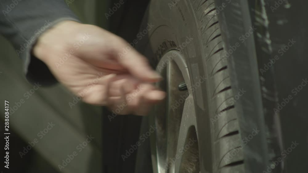 Man unscrews cap from tire valve stem to check pressure and fill with air. Close up. Man unscrews cap from tire valve stem to check pressure and fill with air. Close up.