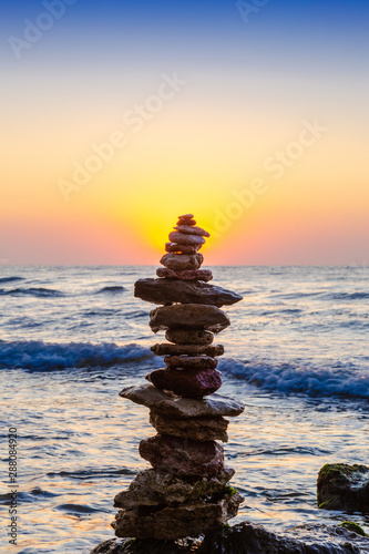 Zen Balancing Pebbles. Stack of pebbles on beach with sunrise on background
