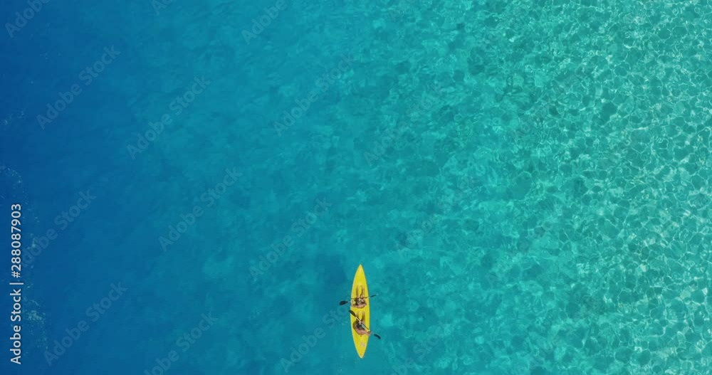 Aerial view of couple tandem kayaking together in deep blue and turquoise ocean water, perfect ocean kayaking in lagoon paradise Aerial view of couple tandem kayaking together in deep blue and turquoise ocean water, perfect ocean kayaking in lagoon paradise