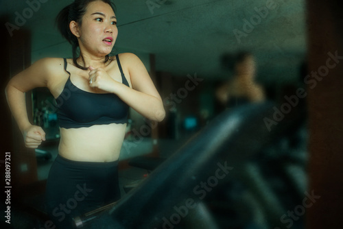 young attractive and fit Asian Korean woman doing running workout at hotel gym or fitness club jogging in treadmill training hard in healthy lifestyle and body care