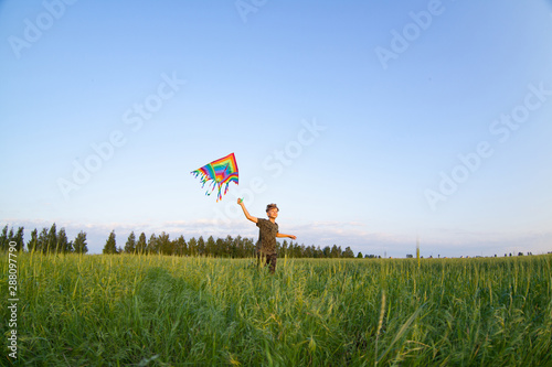 A child plays with a kite at sunset in the field.