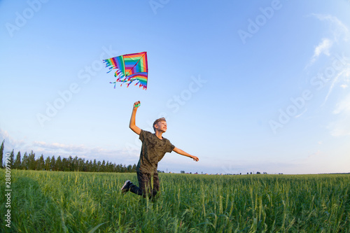 A child plays with a kite at sunset in the field.