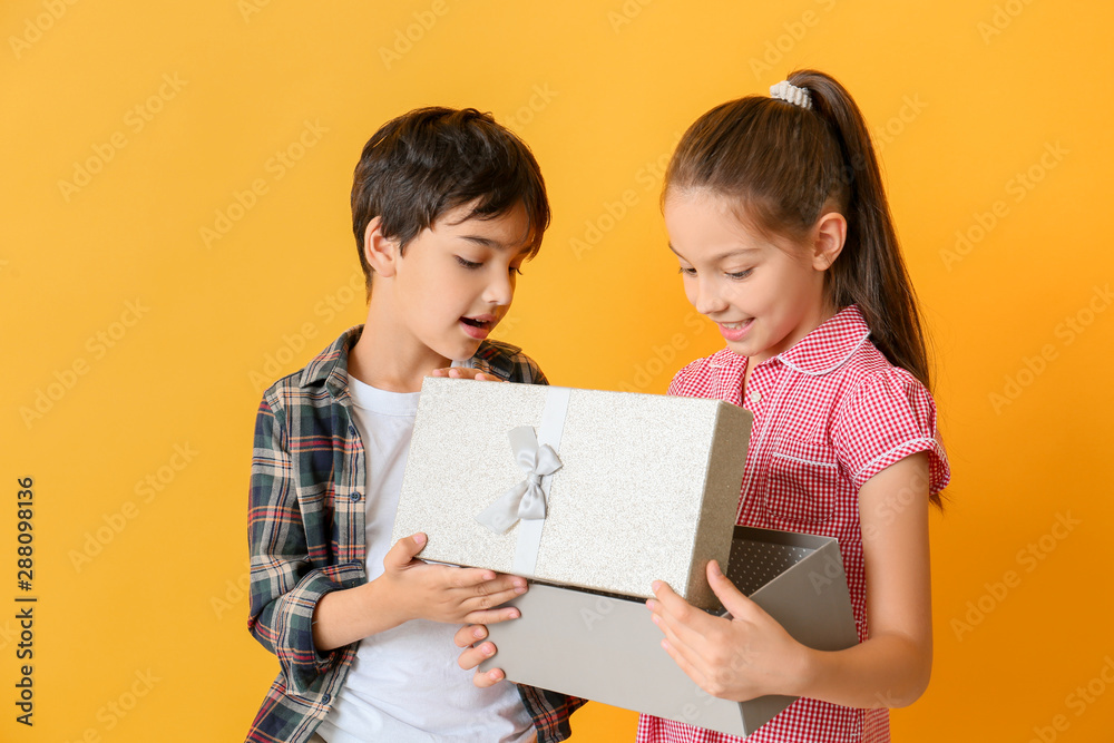 Cute little children opening gift box on color background Cute little children opening gift box on color background