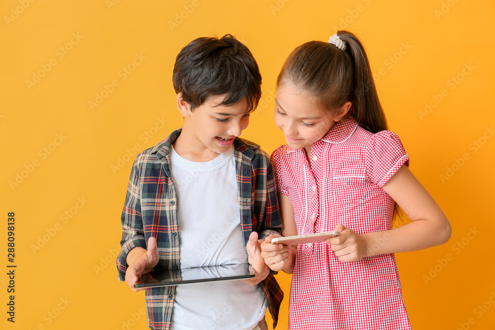 Cute little children with tablet computer and mobile phone on color background Cute little children with tablet computer and mobile phone on color background