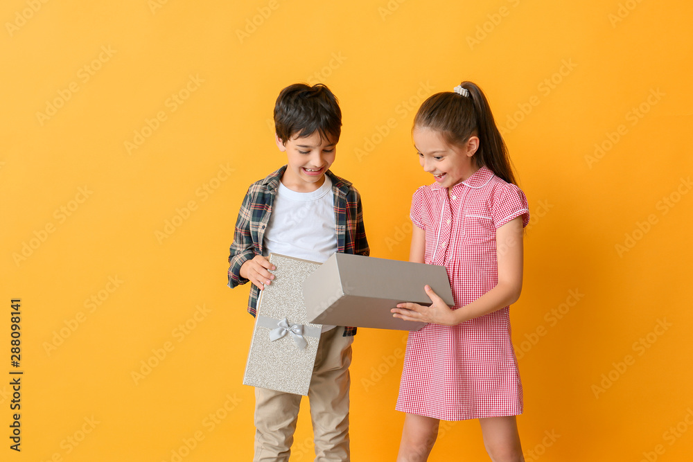 Cute little children opening gift box on color background Cute little children opening gift box on color background