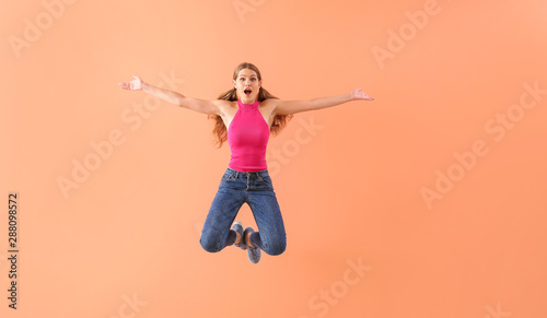 Beautiful jumping young woman on color background
