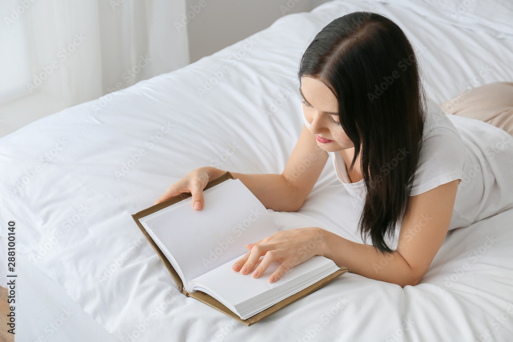 Beautiful young woman reading book in bedroom Beautiful young woman reading book in bedroom
