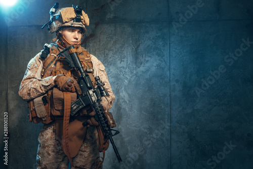 Special forces United States soldier or private military contractor holding rifle. Image on a dark background