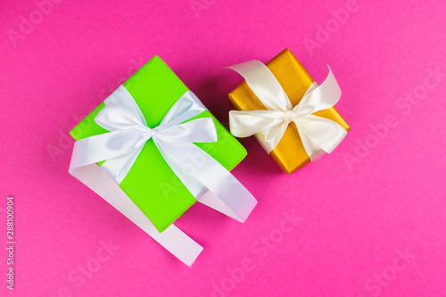 Top view of a decorated present with a bow on pink background
