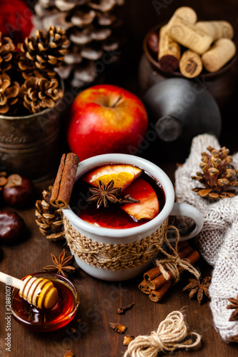 Fototapeta Naklejka Na Ścianę i Meble -  Cozy time at home with a metal mug of hot mulled wine. Autumn, warm clothes, natural ingredients, spice, fruit and honey. Corkscrew to open wine. Rustic decor, festive mood