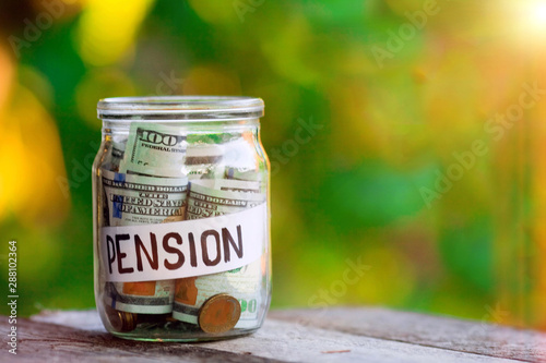 Glass jar with dollars and the word pension paper label. Pension money savings in a glass jar , copy space .